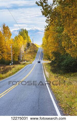 Stock Image - Vehicle driving down a back road, Anchorage, Southcentral Alaska, Autumn. Fotosearch
