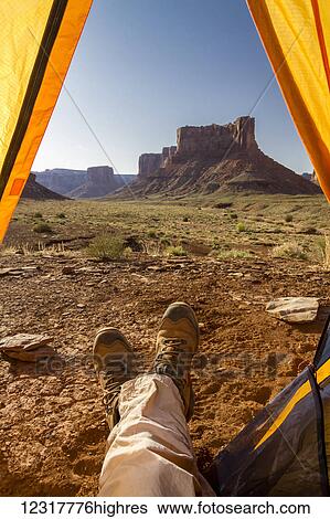 Stock Photograph - View of a camper's feet out of a tent viewing rock cliffs, Canyonlands National Park; Utah, United States of America. Fotosearch