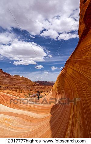 Stock Photograph - View of a hiker in the sandstone formation known as the Wave, Vermillion Cliffs; Arizona, United States of America. Fotosearch