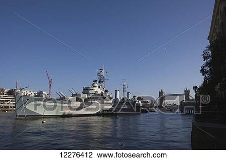 Warship HMS Belfast, docked on the River Thames and part of the Imperial War Museum, view of the Tower Bridge and Canary Wharf in the far distance; London, England View Large Photo Image Stock Image - Warship HMS Belfast, docked on the River Thames and part of the Imperial War Museum, view of the Tower Bridge and Canary Wharf in the far distance; London, England. Fotosearch