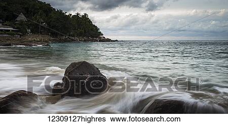 Water flowing over rock at the shore with a view of the coastline under a cloudy sky; Yalepa, Jalisco, Mexico View Large Photo Image Stock Photograph - Water flowing over rock at the shore with a view of the coastline under a cloudy sky; Yalepa, Jalisco, Mexico. Fotosearch