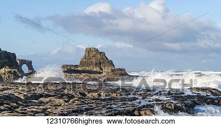 Stock Photograph - Waves splashing onto the rock formations on the coast; South Shields, Tyne and Wear, England. Fotosearch