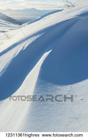 Stock Photograph - Wind swept snow makes interesting sculptures in Independence Mine area in Hatcher Pass, South-central Alaska; Alaska, United States of America. Fotosearch