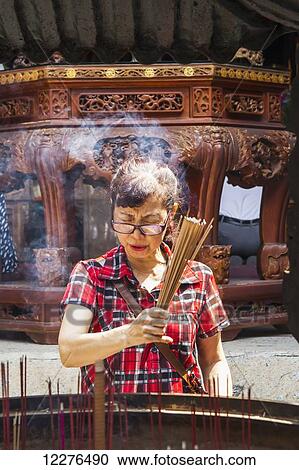 Woman burning incense at the Official God of War Temple; Tainan, Taiwan View Large Photo Image Stock Image - Woman burning incense at the Official God of War Temple; Tainan, Taiwan. Fotosearch