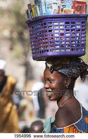 Stock Photograph - Woman carrying a basket on her head in Bamako, Mali. Fotosearch