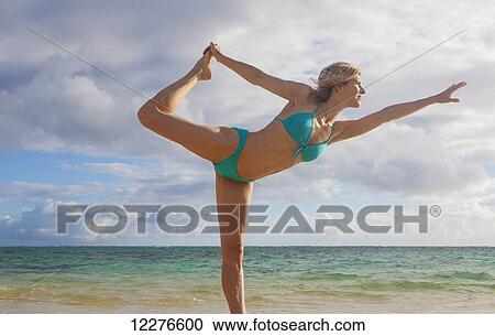 Stock Image - Woman doing yoga on the beach; Kailua, Island of Hawaii, Hawaii, United States of America. Fotosearch