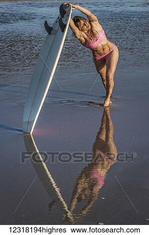 Woman leaning and stretching with her surfboard on the shore; Tarifa, Cadiz, Andalusia, Spain View Large Photo Image Stock Photograph - Woman leaning and stretching with her surfboard on the shore; Tarifa, Cadiz, Andalusia, Spain. Fotosearch