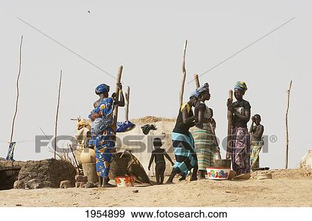 Stock Photo - Woman pounding millet in a village along the shores of the Niger River between Mopti and Lake Debo, Mali. Fotosearch