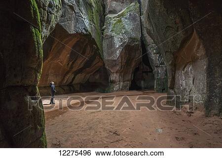 Stock Photograph - Woman standing in a natural cathedral deep within the Cuidad de Itas, Toro Toro National Park; Bolivia. Fotosearch