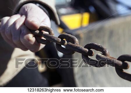 Stock Photograph - Worker's hand on a rusty chain; New Holland, Pennsylvania, United States of America. Fotosearch