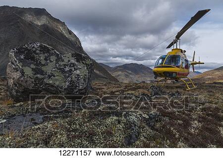 Stock Photo - Yellow helicopter sitting on a mountain top in Tombstone Territorial Park; Yukon, Canada . Fotosearch