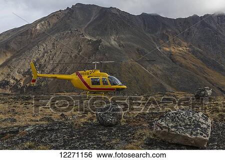Yellow helicopter sitting on a mountain top in Tombstone Territorial Park; Yukon, Canada View Large Photo Image Stock Photograph - Yellow helicopter sitting on a mountain top in Tombstone Territorial Park; Yukon, Canada . Fotosearch