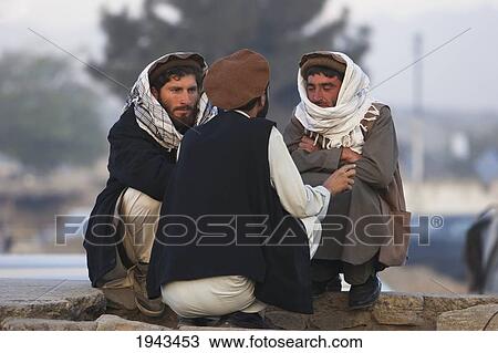 Stock Image - Young Afghan Men Sitting By The Side On A Road In Kabul,, Afghanistan. Fotosearch