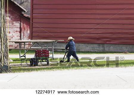 Stock Photo - Young Amish boy playing with a shovel, near Hazelton; Iowa, United States of America. Fotosearch