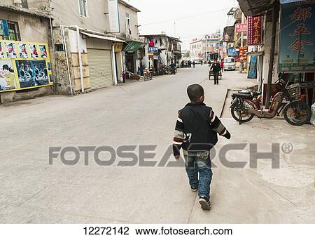 Stock Image - Young boy walks on the street of Tapu village; Xiamen, Fujian province, China. Fotosearch