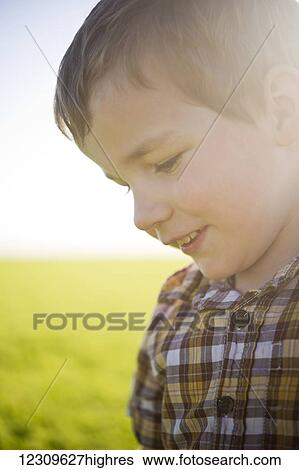 Stock Photograph - Young boy's profile with sunlight hitting his face in a farm field; Saskatchewan, Canada. Fotosearch