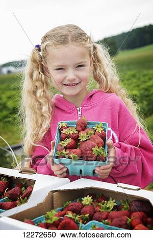 Stock Image - Young girl smiles after helping to pick strawberries on the family farm; Strasburg, Pennsylvania, United States of America. Fotosearch