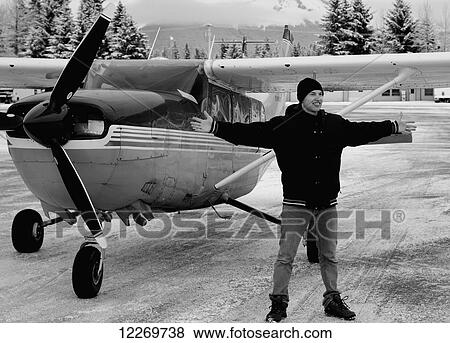 Young man standing with arms outstretched in front of a small airplane, Haines, Southeast Alaska View Large Photo Image Stock Photo - Young man standing with arms outstretched in front of a small airplane, Haines, Southeast Alaska. Fotosearch