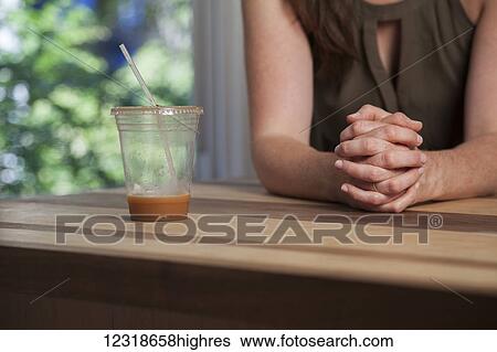 Stock Photograph - Young woman drinking iced coffee in her kitchen; Connecticut, United States of America. Fotosearch