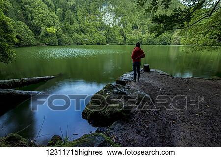 Stock Photograph - Young woman enjoying the calm of Lagoa do Congro; Sao Miguel, Azores, Portugal. Fotosearch