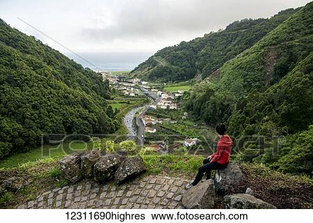 Stock Photograph - Young woman enjoying the view in Faial da Terra; Sao Miguel, Azores, Portugal. Fotosearch