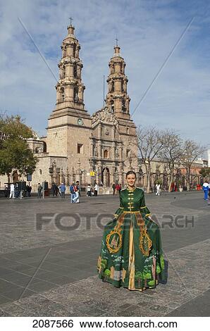 Stock Photograph - Young Woman In A Traditional Dress On La Patria Square In Front Of The Basilica Cathedral, Aguascalientes, Mexico. Fotosearch