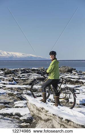Young woman with her bicycle stands on frozen ice chunks along the Tony Knowles Coastal Trail, Anchorage, Southcentral Alaska View Large Photo Image Stock Photography - Young woman with her bicycle stands on frozen ice chunks along the Tony Knowles Coastal Trail, Anchorage, Southcentral Alaska. Fotosearch
