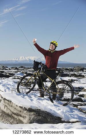 Young woman with her bicycle takes a selfie with a smart phone while standing on frozen ice chunks along the Tony Knowles Coastal Trail, Anchorage, Southcentral Alaska View Large Photo Image Stock Image - Young woman with her bicycle takes a selfie with a smart phone while standing on frozen ice chunks along the Tony Knowles Coastal Trail, Anchorage, Southcentral Alaska. Fotosearch