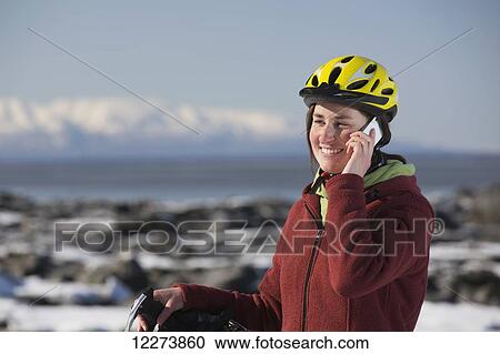 Young woman with her bicycle talks on a cell phone while standing on frozen ice chunks along the Tony Knowles Coastal Trail, Anchorage, Southcentral Alaska View Large Photo Image Stock Image - Young woman with her bicycle talks on a cell phone while standing on frozen ice chunks along the Tony Knowles Coastal Trail, Anchorage, Southcentral Alaska. Fotosearch