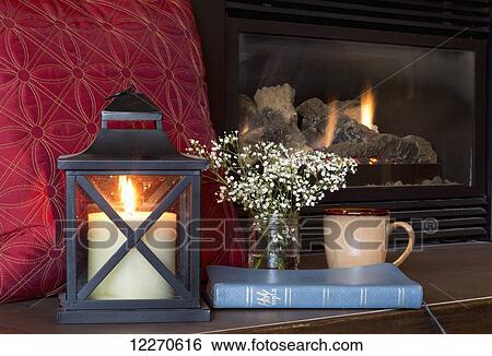 Stock Photograph - A Bible, candle and mug sit on the fireplace hearth; Yarrow, British Columbia, Canada. Fotosearch