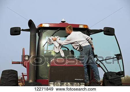 Stock Photo - A farmer cleans the windshield of his tractor during spring corn planting operations, near Northrop; Minnesota, United States of America. Fotosearch