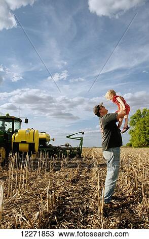 A farmer takes a break from planting no-till soybeans into corn residue to play with his young daughter, near Blue Earth; Minnesota, United States of America View Large Photo Image Stock Image - A farmer takes a break from planting no-till soybeans into corn residue to play with his young daughter, near Blue Earth; Minnesota, United States of America. Fotosearch