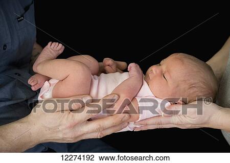 Stock Image - A father and mother holding a newborn baby girl; Chilliwack, British Columbia, Canada. Fotosearch
