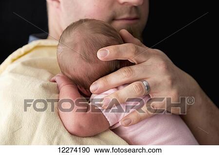 Stock Image - A father holds her newborn daughter; Chilliwack, British Columbia, Canada. Fotosearch