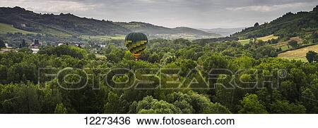 A hot air balloon flies low over a spring valley landscape; Tuscany, Italy View Large Photo Image Stock Photograph - A hot air balloon flies low over a spring valley landscape; Tuscany, Italy. Fotosearch