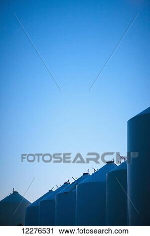 Stock Image - A row of silos against a blue sky; Saskatchewan, Canada. Fotosearch