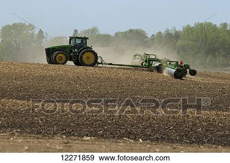 Stock Photo - A tractor pulling a land roller over a recently tilled field prior to planting soybeans, near Truman; Minnesota, United States of America. Fotosearch