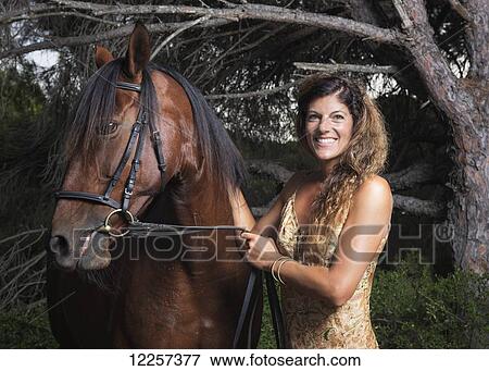 Stock Photo - A woman standing with a horse; Tarifa, Cadiz, Andalusia, Spain. Fotosearch