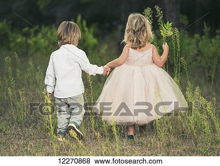 Stock Photo - A young boy and young girl holding hands and walking through a field; Tarifa, Cadiz, Andalusia, Spain. Fotosearch