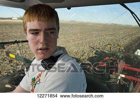 A young farmer in the cab of a tractor carefully monitors the disking of a field prior to planting, near Northrop; Minnesota, United States of America View Large Photo Image Picture - A young farmer in the cab of a tractor carefully monitors the disking of a field prior to planting, near Northrop; Minnesota, United States of America. Fotosearch