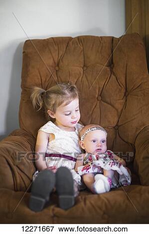 Stock Photo - A young girl and baby girl sit and cuddle on the couch after meeting for the first time; Manhattan Beach, California, United States of America. Fotosearch