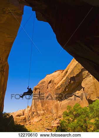 Stock Image - Adventurer rappelling down a desert slot canyon; Hanksville, Utah, United States of America. Fotosearch