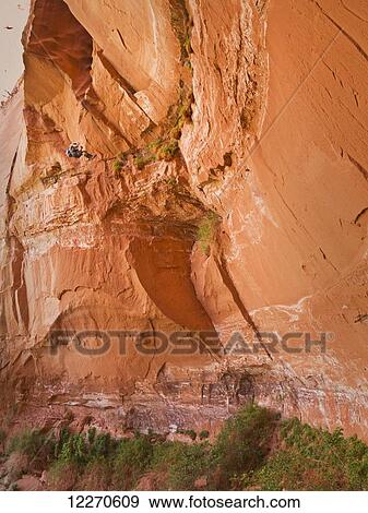 Stock Photo - Adventurer rappelling down a desert slot canyon; Hanksville, Utah, United States of America. Fotosearch