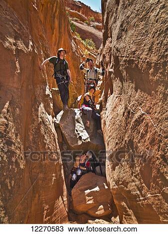 Stock Image - Adventurers exploring a desert slot canyon; Hanksville, Utah, United States of America. Fotosearch