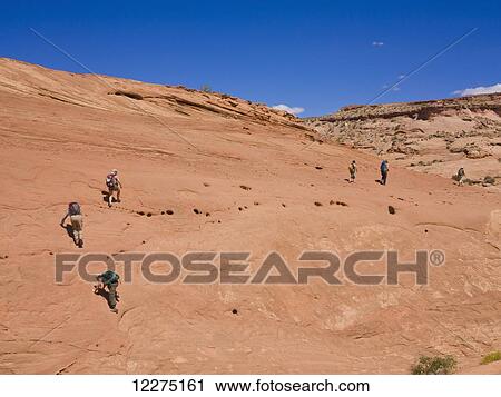 Stock Image - Adventurers exploring a desert slot canyon; Hanksville, Utah, United States of America. Fotosearch