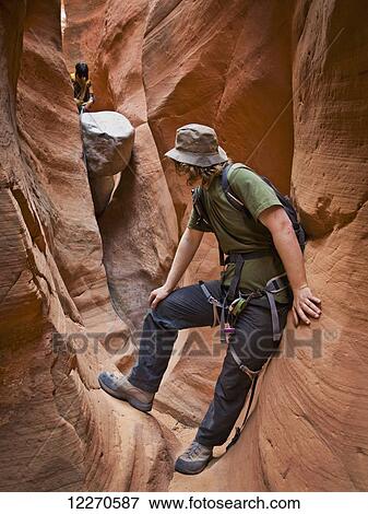 Adventurers exploring a desert slot canyon; Hanksville, Utah, United States of America View Large Photo Image Stock Photo - Adventurers exploring a desert slot canyon; Hanksville, Utah, United States of America. Fotosearch