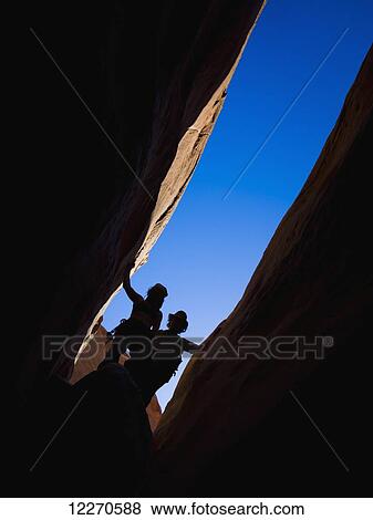 Stock Photo - Adventurers exploring a desert slot canyon; Hanksville, Utah, United States of America. Fotosearch