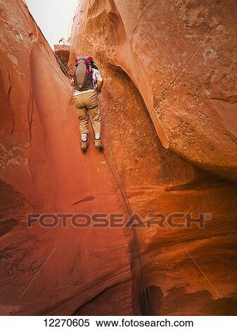 Stock Photography - Adventurers exploring a desert slot canyon; Hanksville, Utah, United States of America. Fotosearch