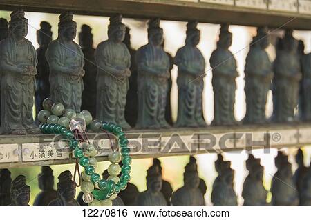 Buddhist bracelet wrapped around a temple figurine among many; Ohara, Kyoto, Japan View Large Photo Image Stock Photograph - Buddhist bracelet wrapped around a temple figurine among many; Ohara, Kyoto, Japan. Fotosearch
