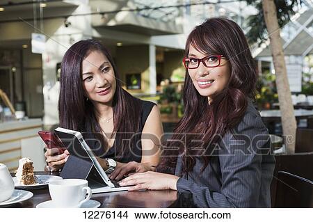 Businesswoman training a co-worker in a coffee shop at a shopping complex; St. Albert, Alberta, Canada View Large Photo Image Picture - Businesswoman training a co-worker in a coffee shop at a shopping complex; St. Albert, Alberta, Canada. Fotosearch